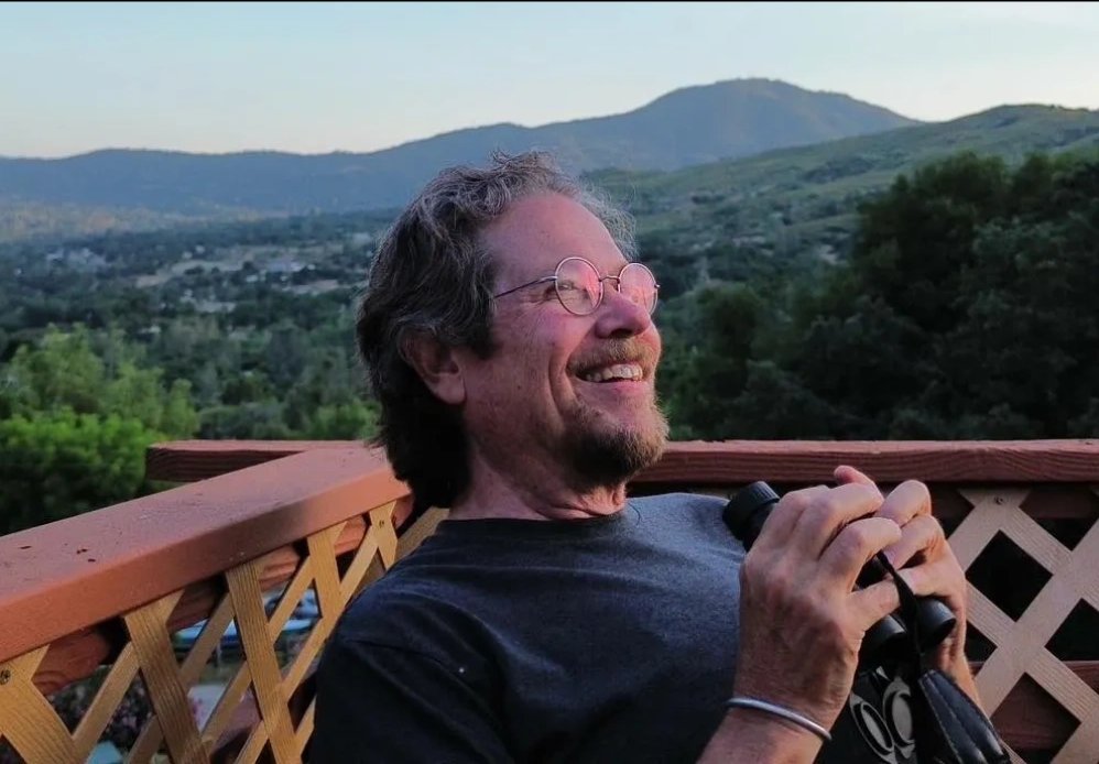 Walt Edinger smiling on a deck overlooking green hills